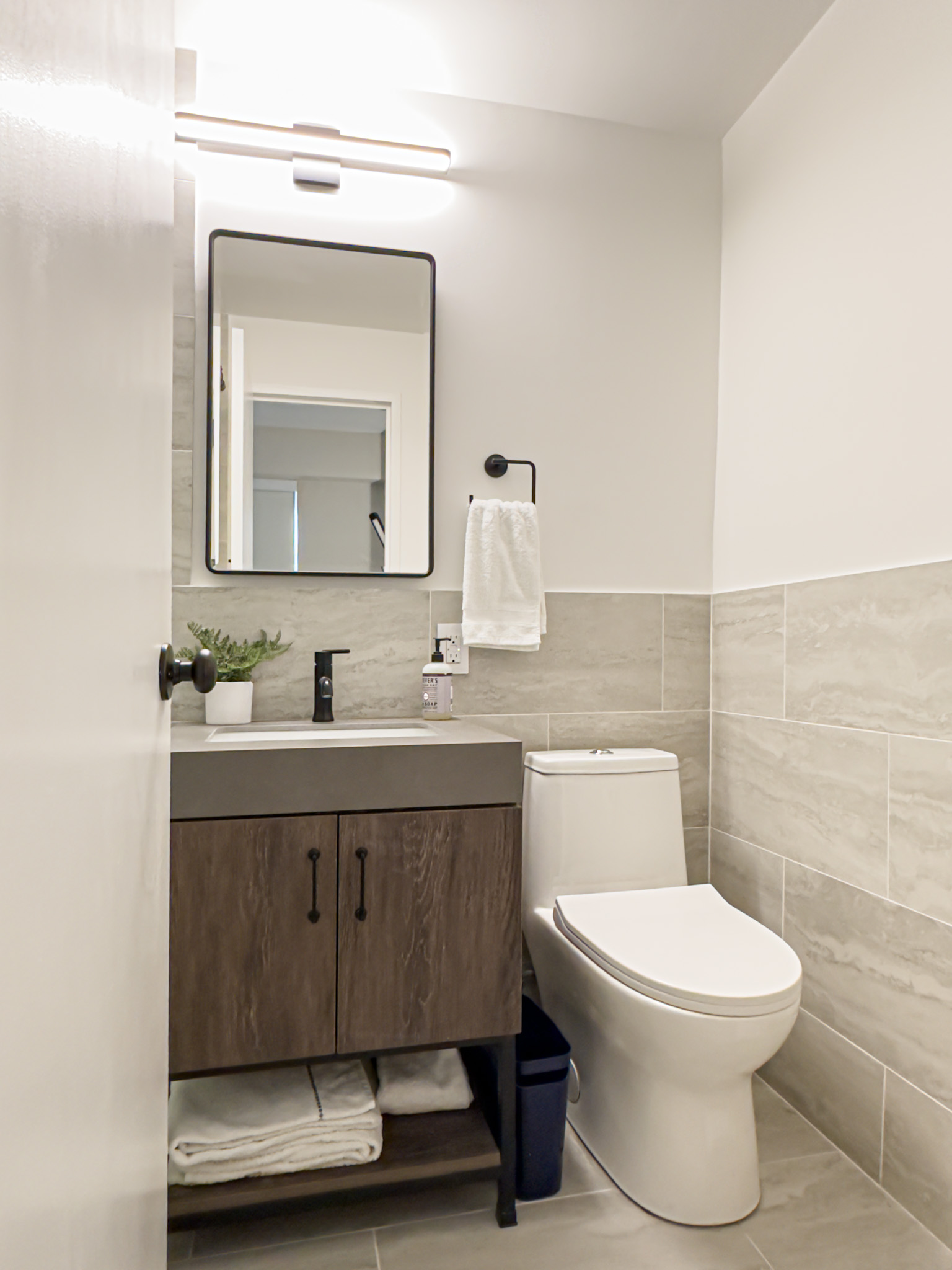 Bathroom — travertine tile, wood vanity, matte black fixtures